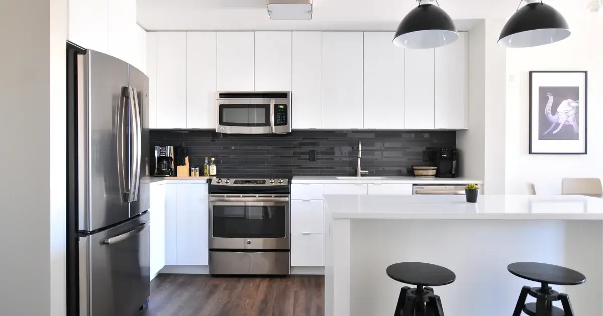 A kitchen with white cabinets and black tile