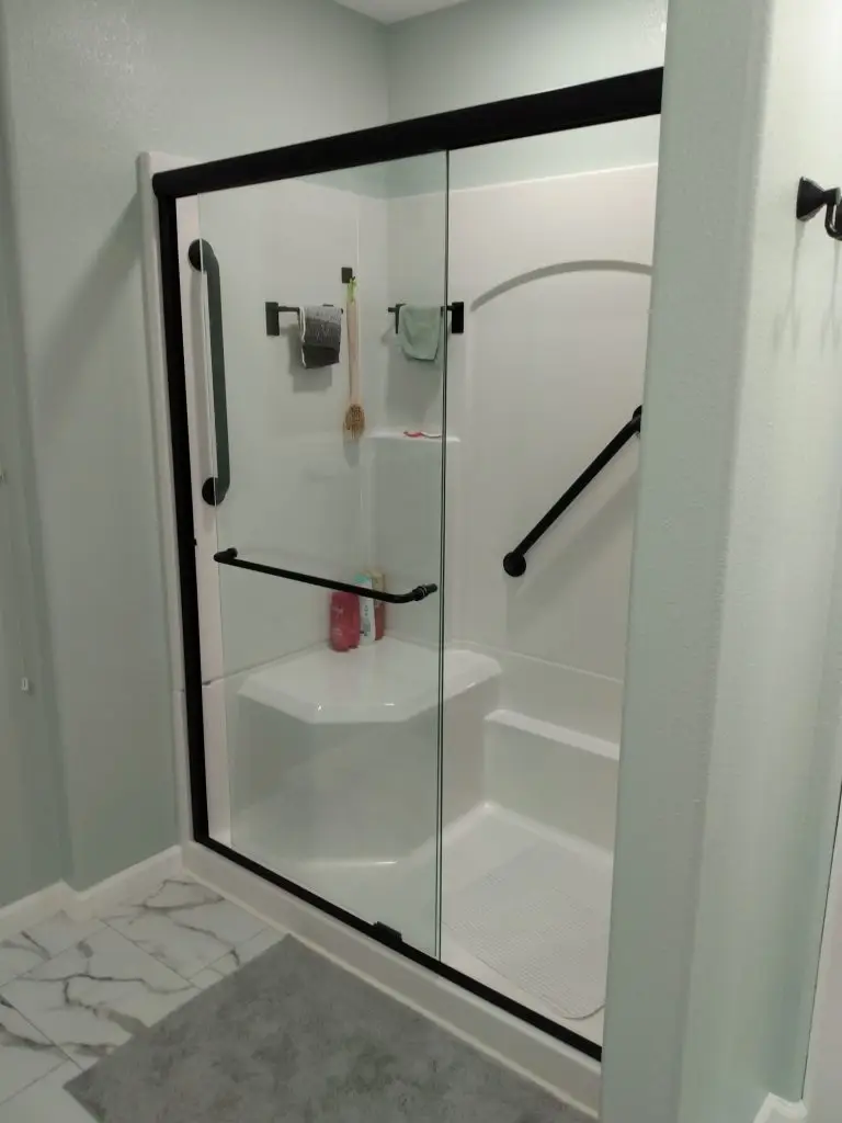 Newly remodeled shower with glass enclosure and grab bars, showcasing accessible bathroom remodeling and full