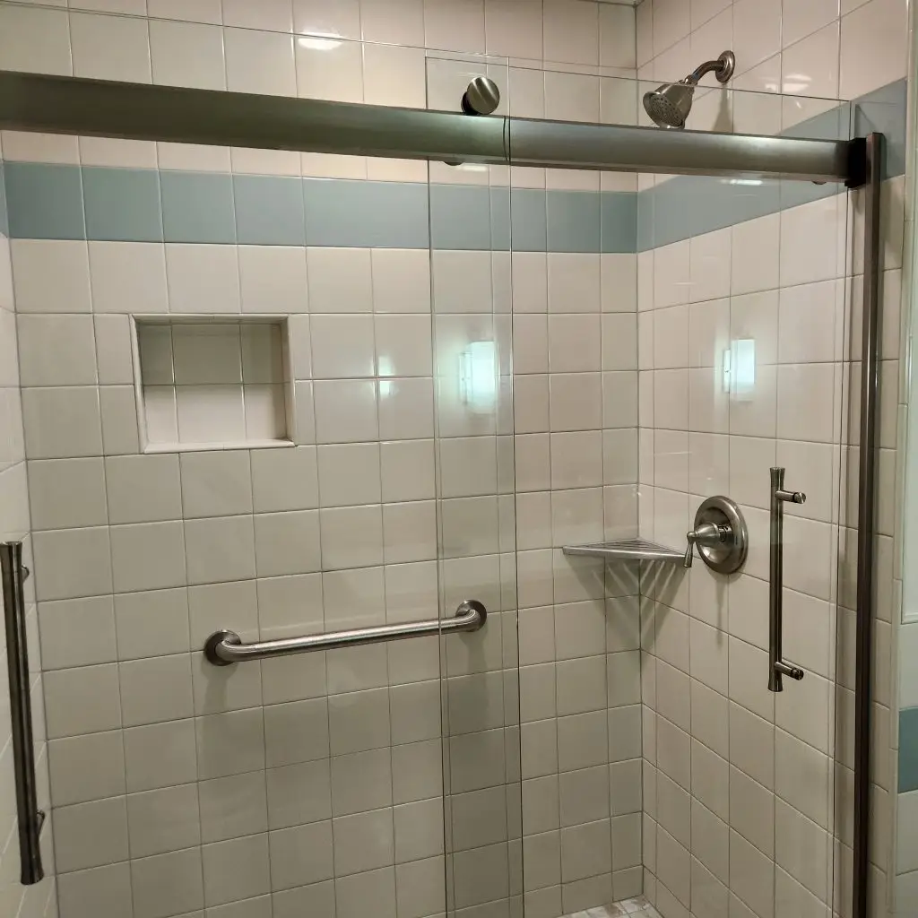 Newly remodeled shower with glass enclosure, tile walls, and grab bars, showcasing accessible bathroom design