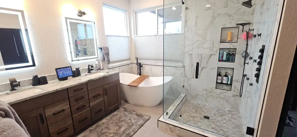 Newly remodeled bathroom featuring a custom tile walk-in shower with built-in niches, a freestanding soaking