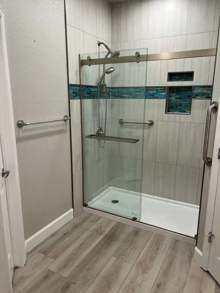 Newly remodeled accessible shower with glass enclosure and gray tile, showcasing a tub-to-shower conversion project